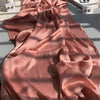 Fließender, staubrosa Crinkle-Satin-Chiffon-Hijab elegant in Sonnenlicht drapiert.