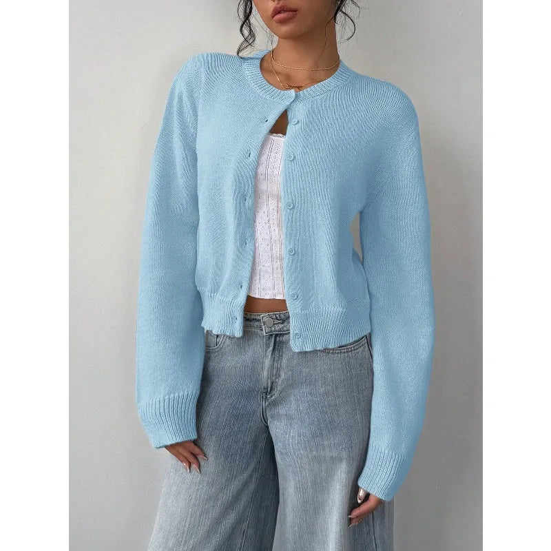 Une femme portant un pull en tricot bleu clair sur un haut blanc et un jean en denim.