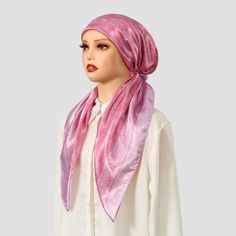 Una mujer modela un turbante instantáneo de satén rosa con estampado floral y una blusa blanca.