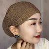 Nahaufnahme einer Frau mit elegantem braunem elastischem Kopftuchhut, verziert mit Strass.