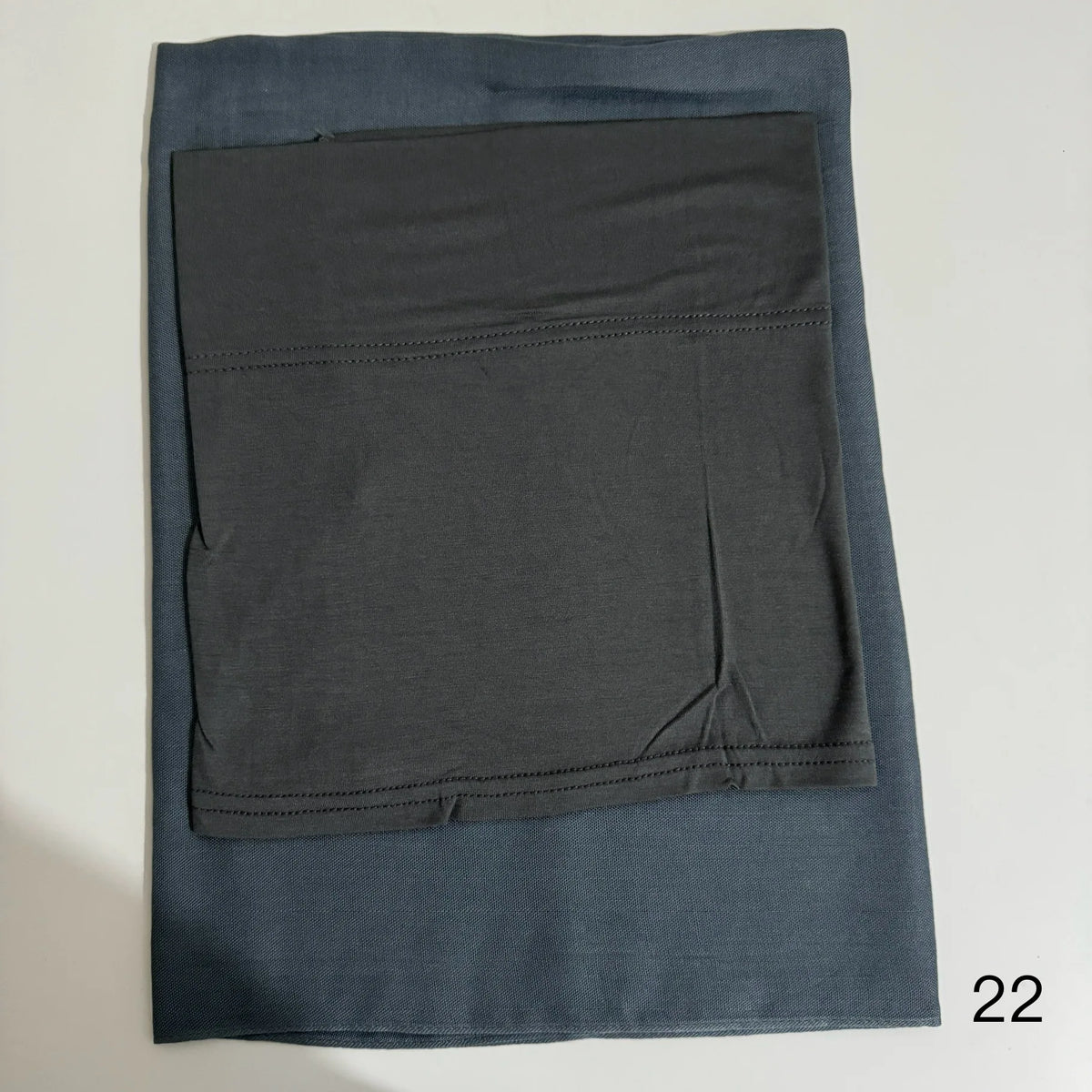 A dark blue soft modal rayon hijab set folded flat, showing the fabric texture and stitching details.