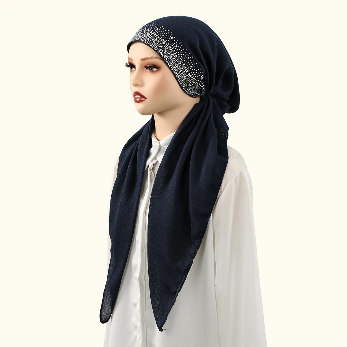 Una mujer vistiendo un gorro interior de lino azul marino con adornos plateados y una blusa blanca.