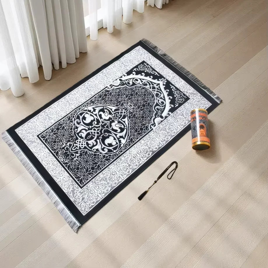 Una elegante alfombra de oración islámica en blanco y negro con intrincado trabajo de cuentas, colocada sobre un suelo de mad
