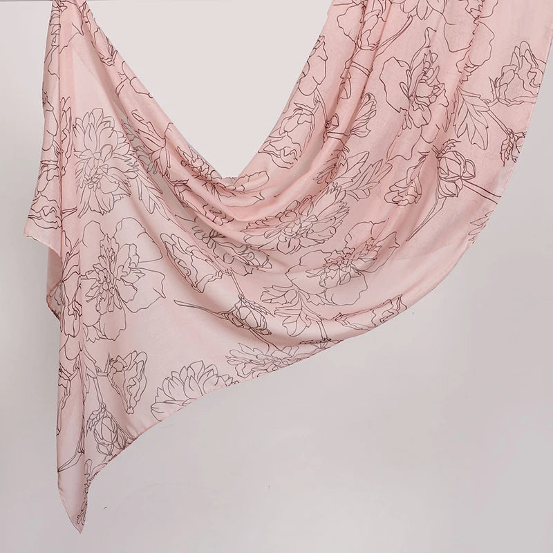 Weiches rosa Überwurf-Schal mit zartem Aquarell-Blumenmuster, elegant drapiert.