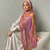 Una mujer vistiendo un pañuelo hijab fluido con estampado de acuarela en tonos rosa, morado y amarillo.