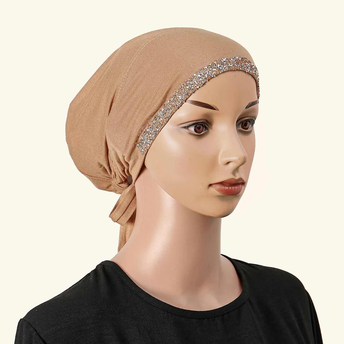 Ein Model trägt einen beige Hijab mit einem verziertem Strassband auf der Stirn und einem schwarzen Oberteil.