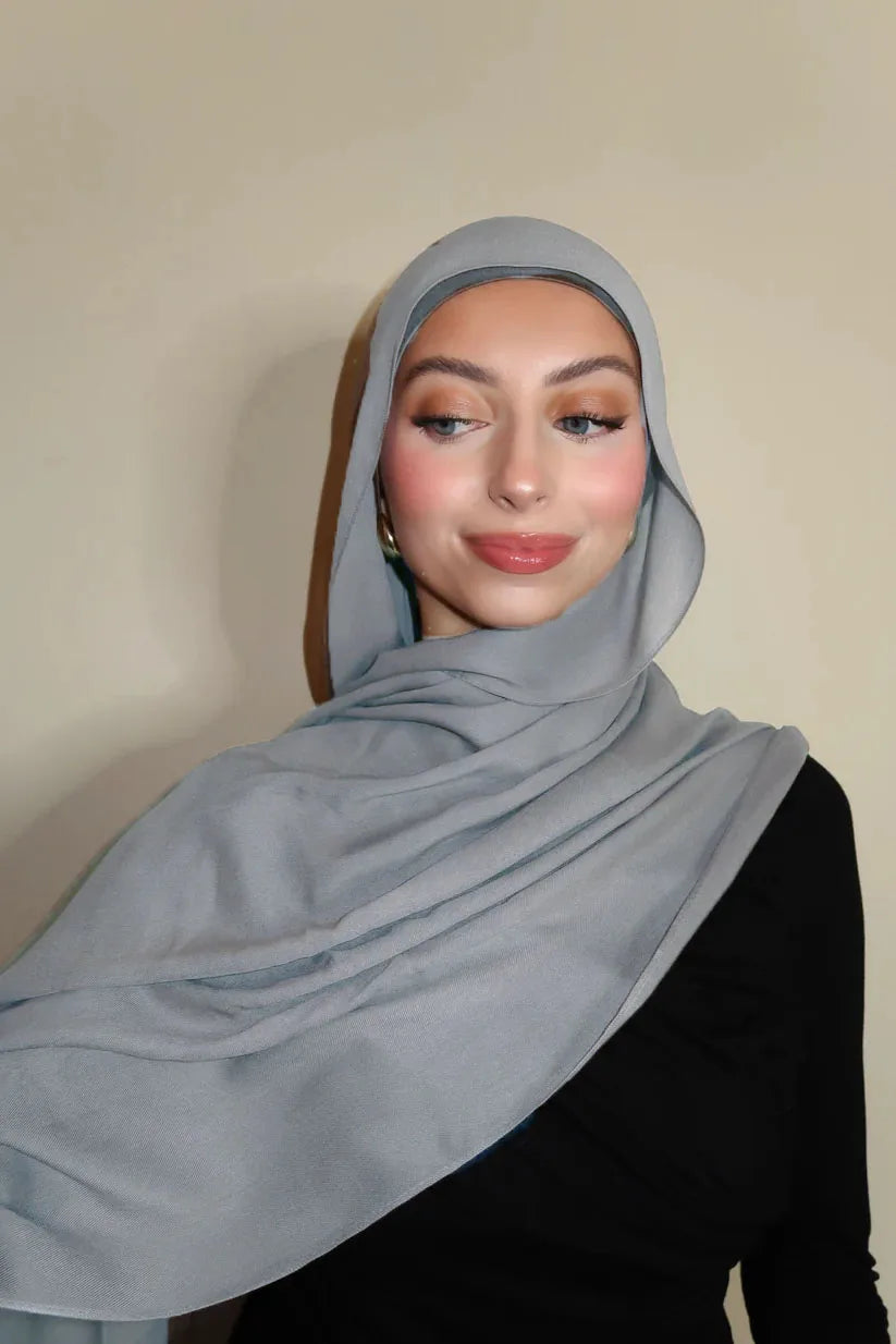 Eine Frau trägt einen hellgrauen Farbverlauf-Rayon-Modalschal und schwarze Kleidung.