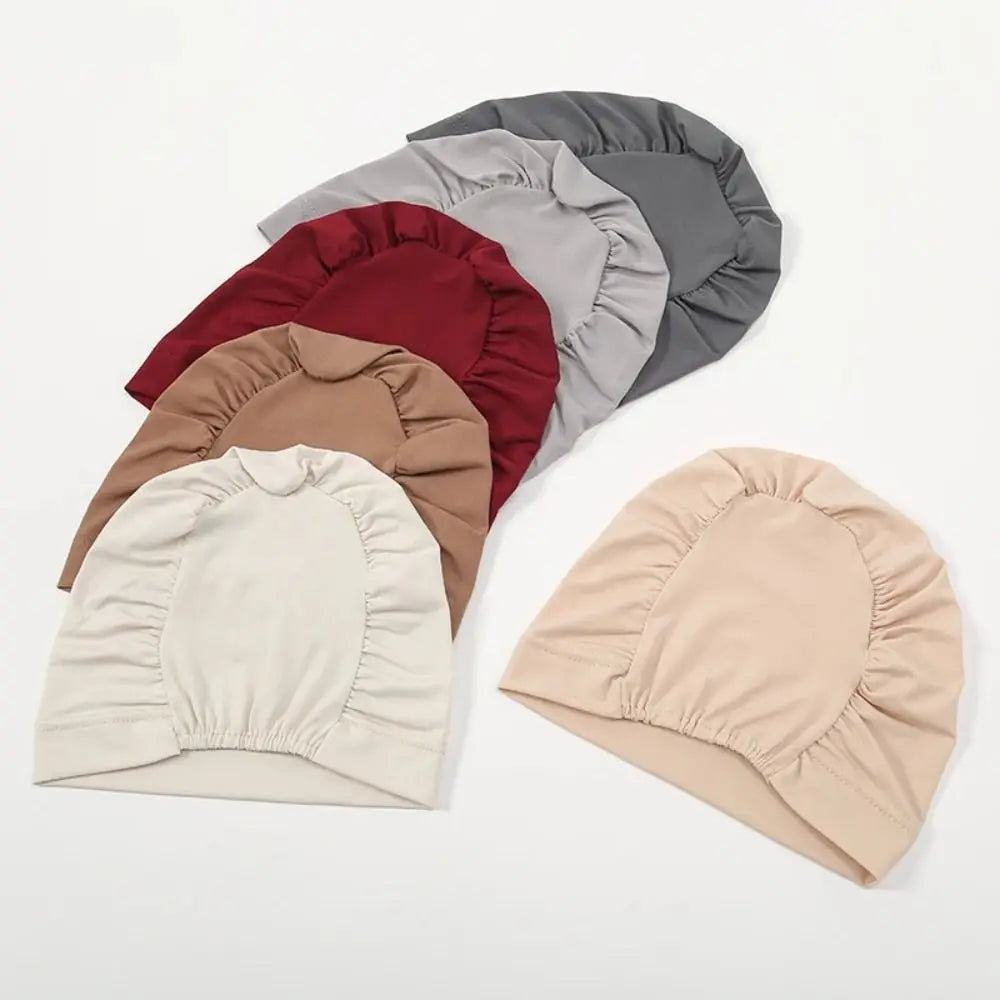 A collection of five breathable cotton underscarfs in shades of maroon, gray, beige, and cream.