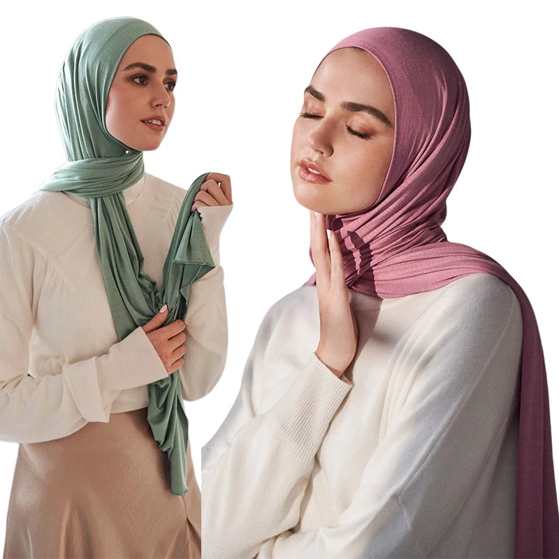A woman wearing a pink modal jersey hijab and white top looking to the side.