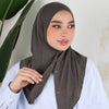 Eine Frau trägt eine dunkel olivgrüne Baumwoll-Jersey-Instant-Sport-Hijab mit einem weißen Oberteil.