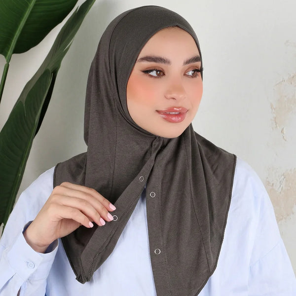 A woman wearing a dark olive green cotton jersey instant sport hijab with a white top.