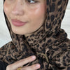 Una mujer vistiendo un pañuelo hijab de estampado leopardo marrón con detalles dorados.