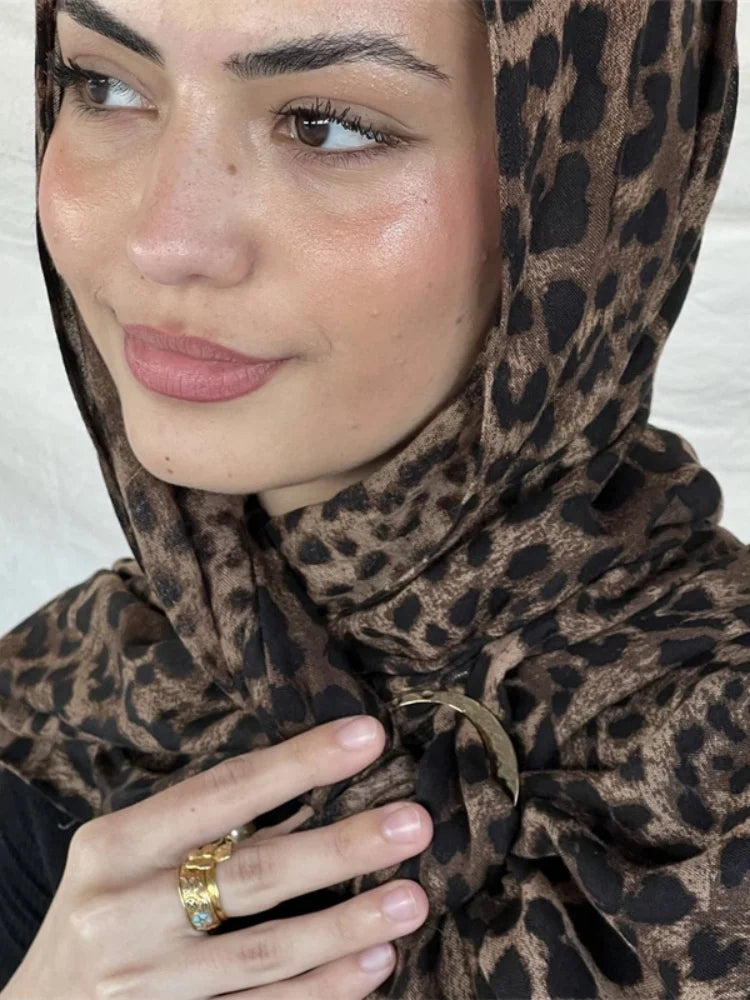 Una mujer vistiendo un pañuelo hijab de estampado leopardo marrón con detalles dorados.
