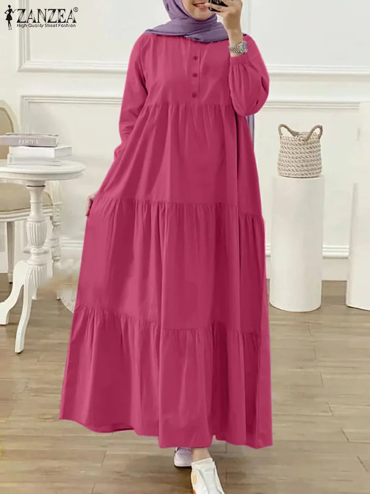 Eine Frau in einem langen, fließenden magentafarbenen muslimischen Kaftankleid mit lila Hijab und silberner Schmuck.
