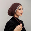 Eine Frau trägt einen dunkelbraunen Samt-Hijab mit funkelnder Strassverzierung auf der Stirn.