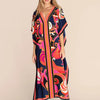 Una mujer modela un vestido caftan de playa azul marino con vibrantes estampados florales y a rayas.
