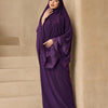 Eine Frau trägt ein elegantes, mehrlagiges Spitzen-Khimar-Abaya-Set in tiefem Violett vor neutralem Hintergrund.