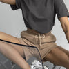 Una persona vistiendo una camiseta básica gris oversize de algodón y pantalones cortos color caqui, sentada en una silla con 