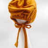 Pañuelo turbante de modal amarillo mostaza atado con cinta, exhibido en maniquí blanco.