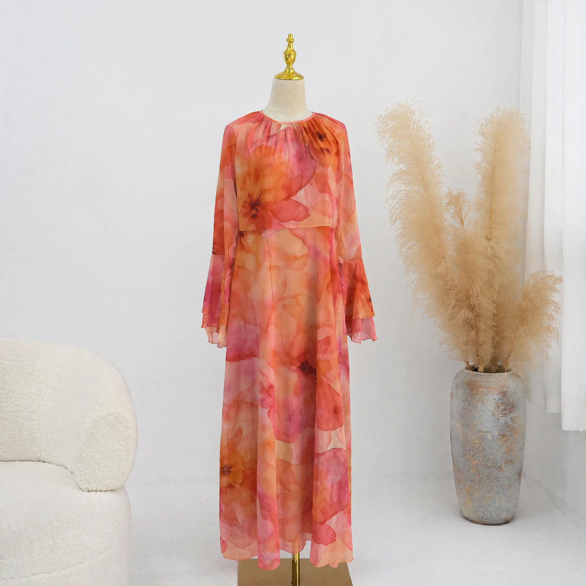 Fließendes, langärmeliges Abaya oder Kaftan-Kleid mit leuchtendem Koralle- und Pink-Blumenmuster auf einem Mannequin.