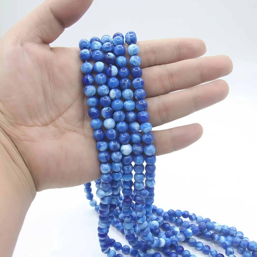 Una mano sostiene una cuenta de cuentas de vidrio azul usadas como tasbih musulmán con borlas de luna y estrella.