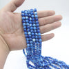 Una mano sostiene una cuenta de cuentas de vidrio azul usadas como tasbih islámico con borlas de luna y estrella.