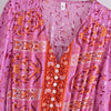 A pink floral maxi dress with orange embroidery and lantern sleeves displayed on a hanger.
