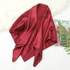 A deep maroon silk satin hijab scarf draped over a white fluffy surface.