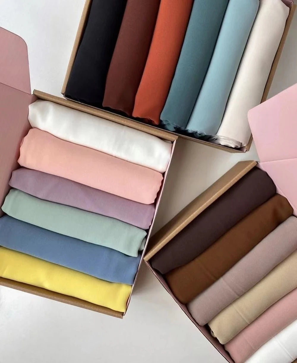 Sechs Chiffon-Hijabstoffrollen in gedämpften und pastelligen Farben in einer Holzbox.