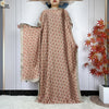 Model in a flowing, reddish-brown patterned kaftan dress with a sheer overlay and wide sleeve.