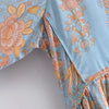 Close-up of a light blue bohemian floral maxi dress featuring detailed pink and yellow botanical print on the sleeve.