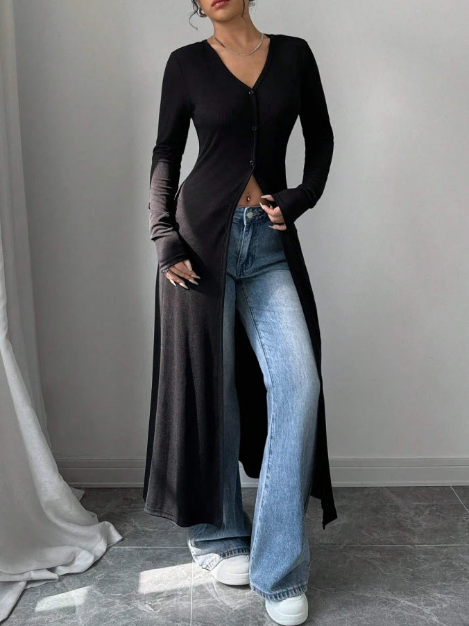 Eine Frau trägt einen schwarzen gerippten Strick-Maxi-Cardigan über blauen Jeans.