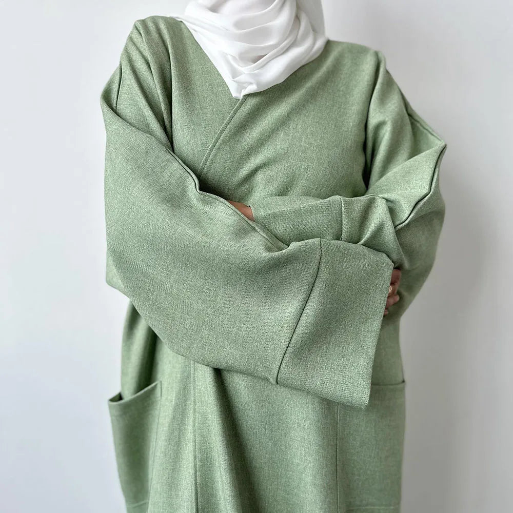 Eine Frau in einem salbeigrünen Leinen-Kimono und einer weißen Hijab.