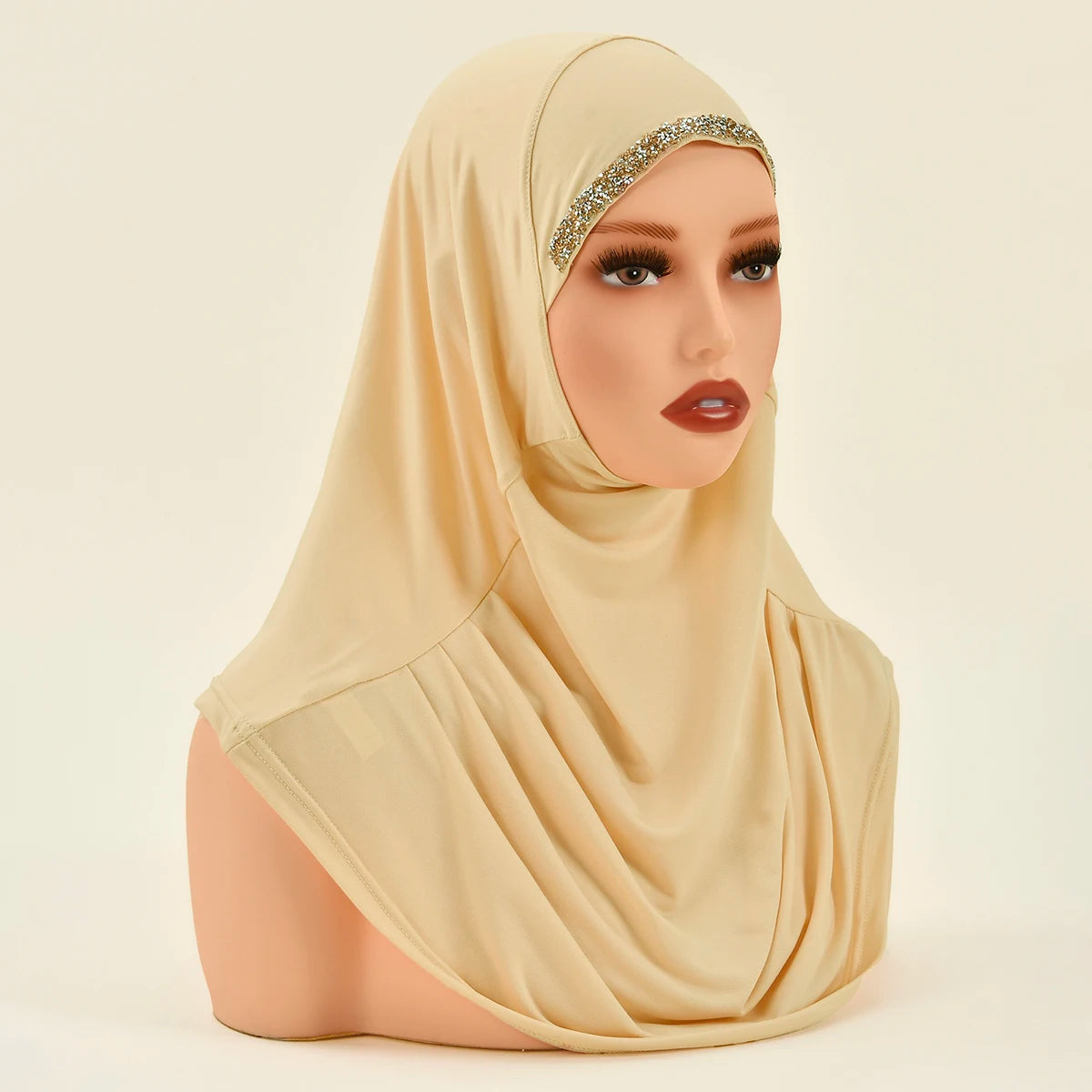 Model trägt einen beige Instant-Hijab mit goldenen Verzierungen.