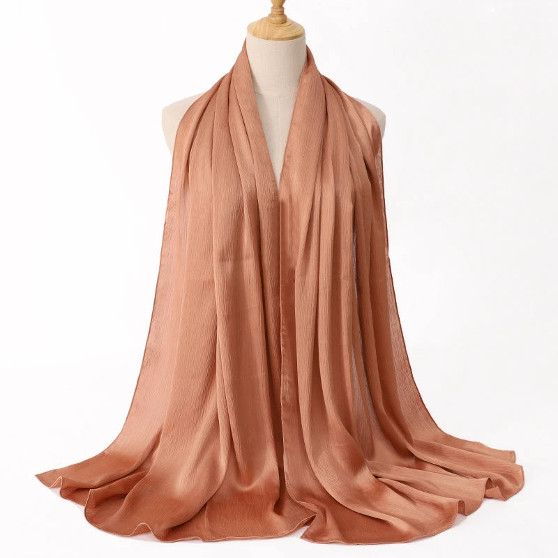 Fließender, rostfarbener Satin-Crinkle-Hijab-Schal um den Hals einer Mannequin drapiert.
