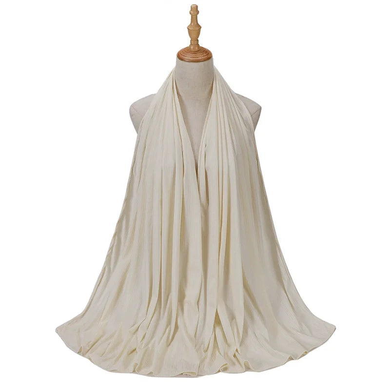 Bufanda de jersey de algodón, color crema, drapeada alrededor del cuello de un maniquí.