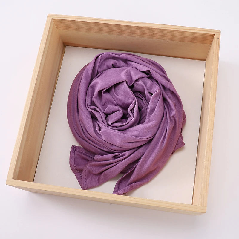 Lila Turban-Schal in Jersey-Stoff, fest gerollt und in einem hellen Holzrahmen präsentiert.