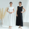 A woman models a white flowing modest abaya dress for women in a studio setting.
