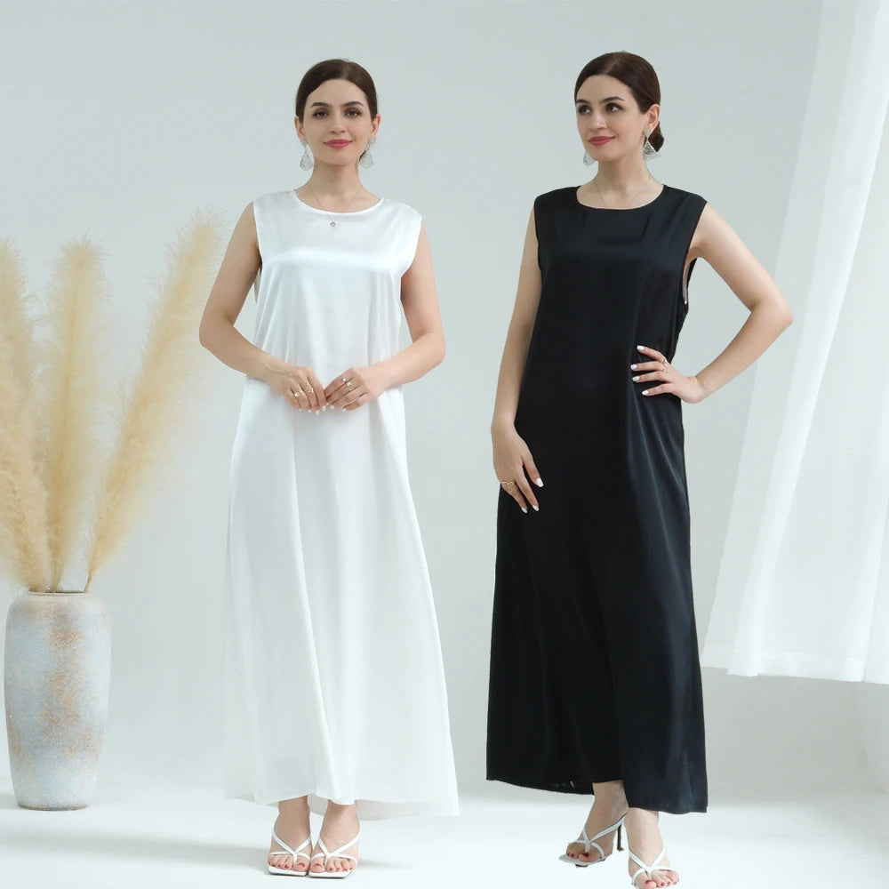 A woman models a white flowing modest abaya dress for women in a studio setting.
