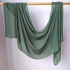 Foulard modal vert uni drapé suspendu sur un bâton en bois.