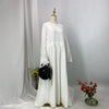 Weiße elegante Batwing-Abaya auf einem Mannequin mit goldenem Finial und schwarzer Handtasche.