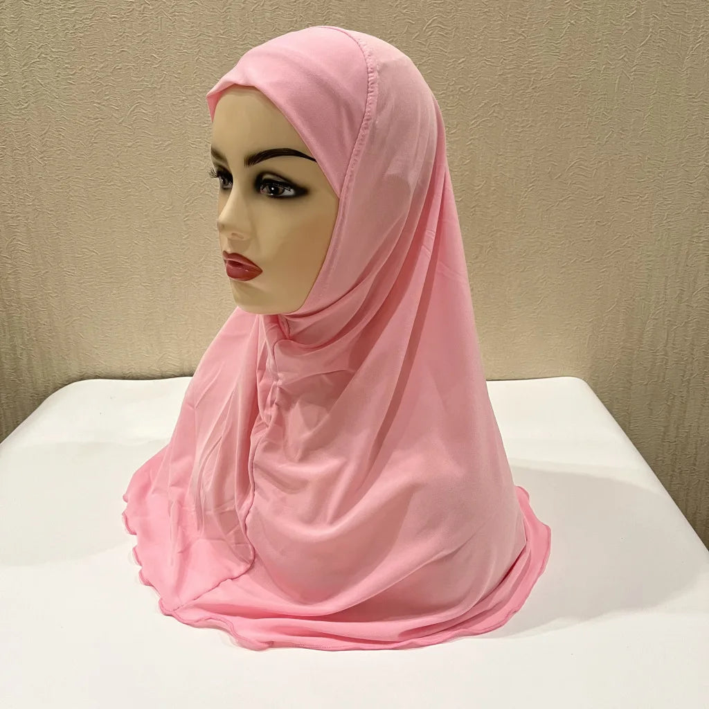 Un chal de hijab rosa para niños drapeado sobre una cabeza de maniquí.