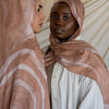 Retrato de cerca de una mujer vistiendo un pañuelo hijab estampado leopardo color rosa polvoriento y ropa blanca.