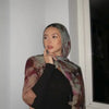 Eine Frau trägt einen mit Aquarell-Blumenmuster bedruckten Modal-Schal-Hijab über einem schwarzen Oberteil.