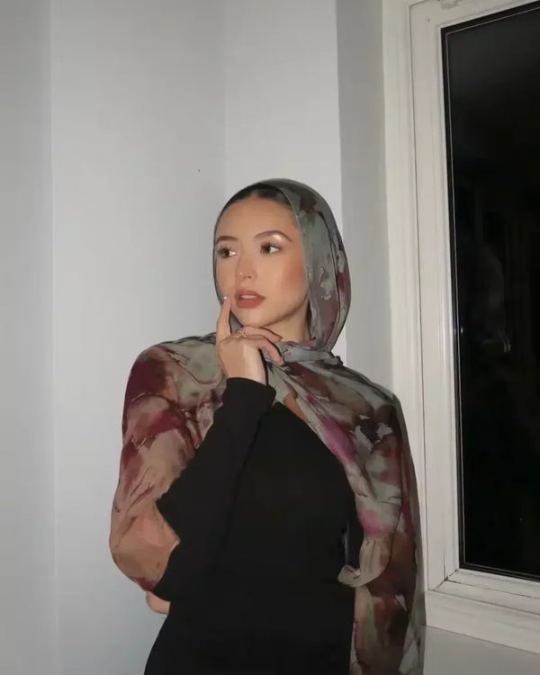 A woman wearing a watercolour floral printed modal shawl hijab scarf with a black top.
