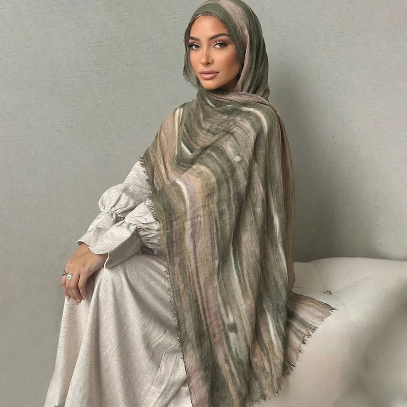 Una mujer vistiendo un pañuelo hijab floral de acuarela bohemio a rayas y un conjunto a juego.