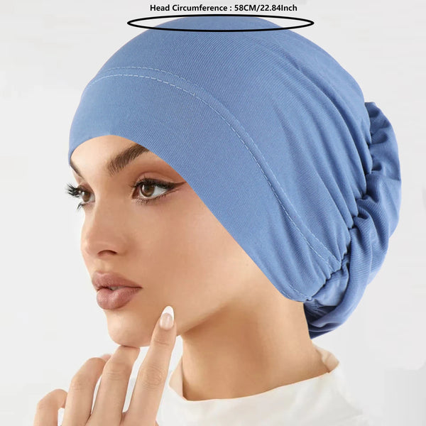 A close-up of a woman wearing a light blue stretch turban cap on her head.