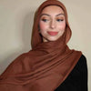 Eine Frau trägt einen einfarbigen braunen Gradient-Rayon-Modal-Hijab und schwarze Kleidung.
