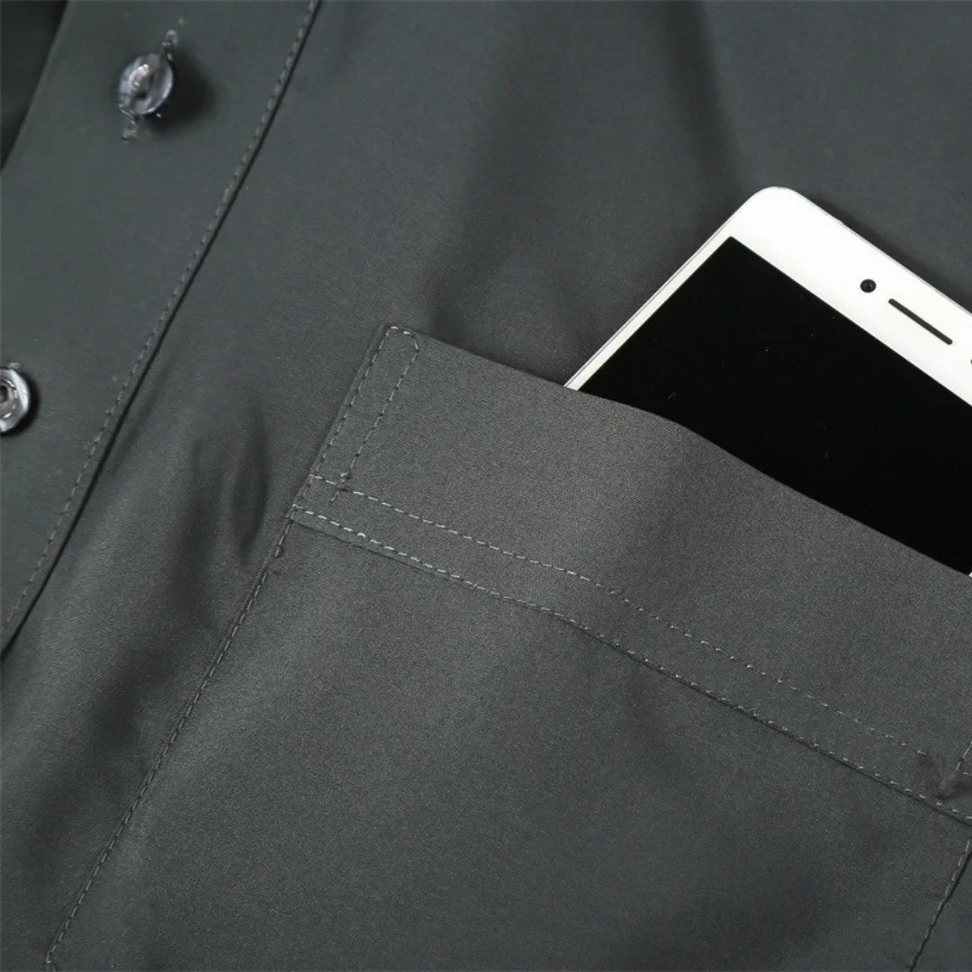 Nahaufnahme eines dunkelgrauen Herren-Überkleids mit arabem Stehkragen und Langarm, einer Tasche und einem Smartphone.