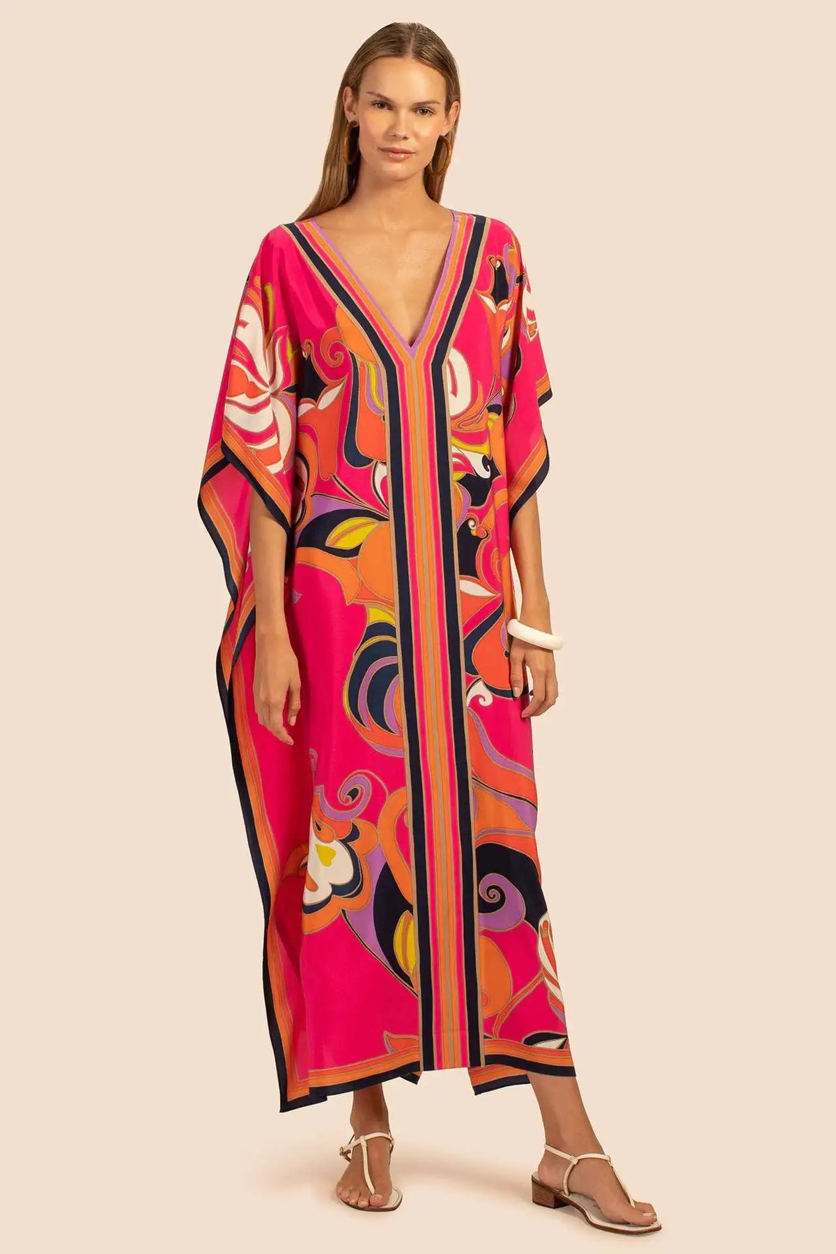 Modelo vistiendo un caftán de playa estampado bohemio rosa y naranja vibrante.